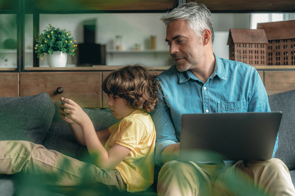 Father looking at his sons phone over his shoulder.