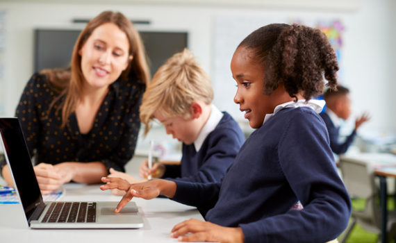 Mom sitting with two children looking at a laptop screen.