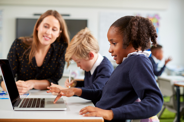Mom sitting with two children looking at a laptop screen.