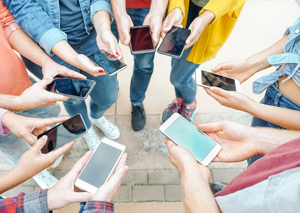 Group of people standing in a circle looking at their phone.