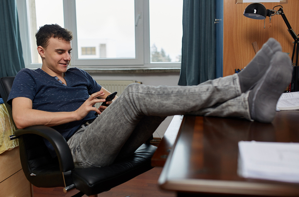 Teenage boy sitting at a desk with a phone.