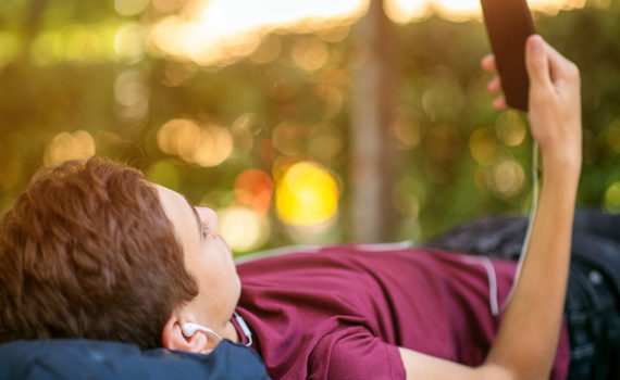 Teen lying down looking at his phone.