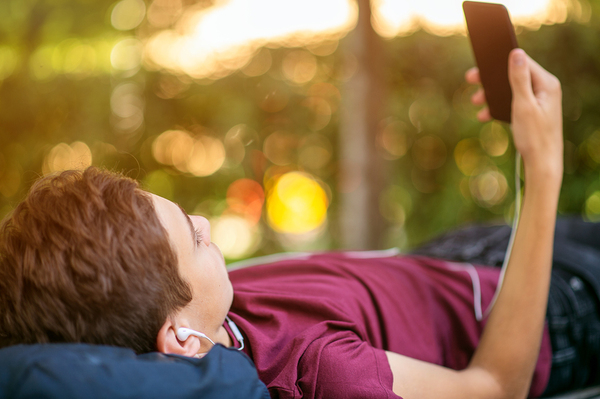 Teen lying down looking at his phone.